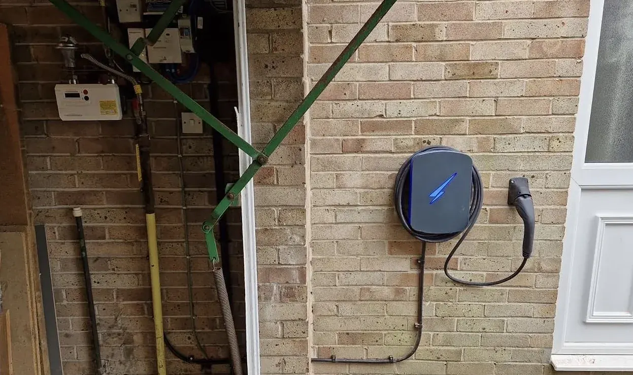 EV charger mounted beside the meter cupboard on a yellow brick wall